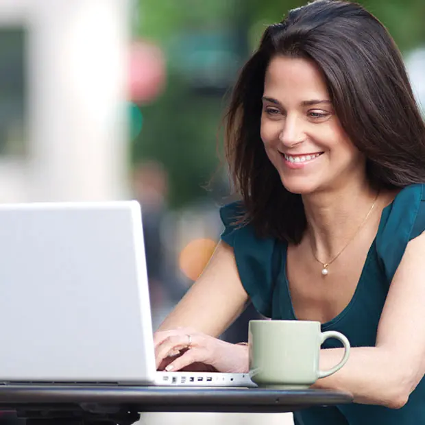 Woman smiling while looking at her computer screen