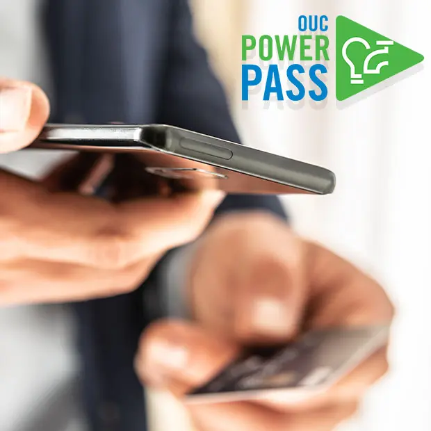 OUC Power Pass: hands hold a cell phone and a credit card