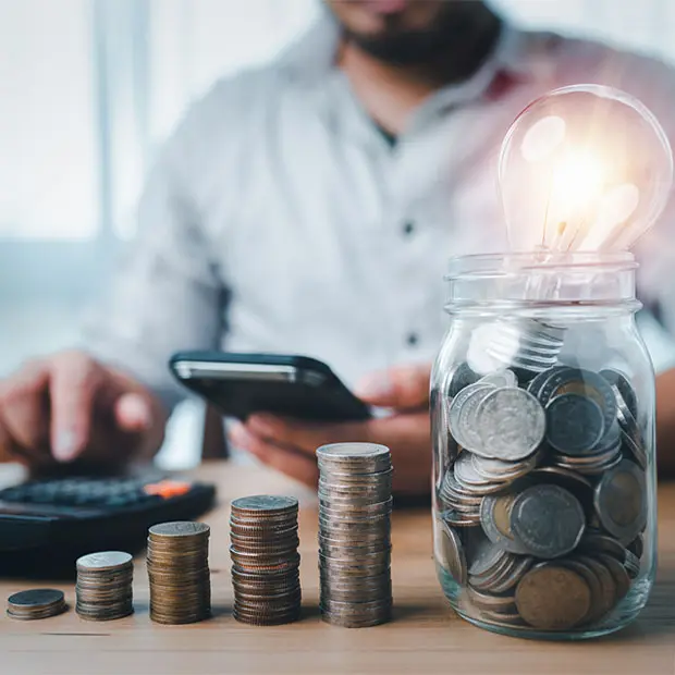 Man using a calculator while a jar of change sits in front of him