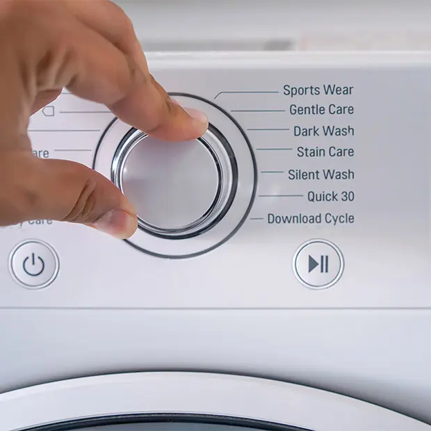 Washing machine dial with hand adjusting the settings of the cycle
