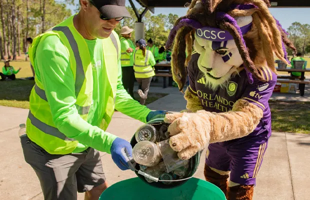 OUC volunteer collects trash at a clean up event