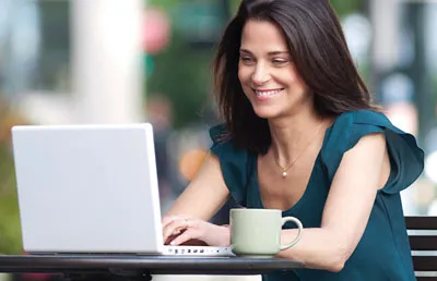 Budget Billing, woman smiling while looking at her computer screen.