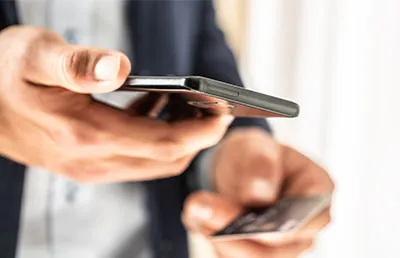 A man looking at his phone and holding a credit card.
