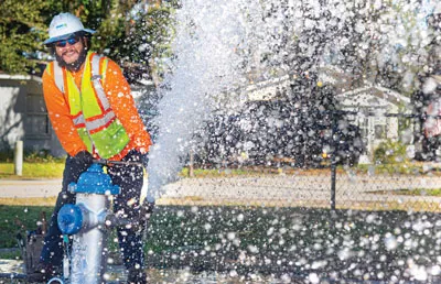 An OUC employee standing near a fire hydrant that is releasing water.