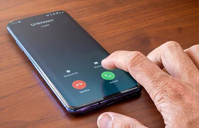 A hand about to answer a call from a scammer.