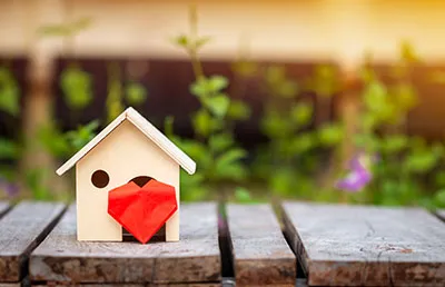 A decorative image of a small toy house with a paper heart.