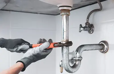 A plumber repairing the pipe under a sink.