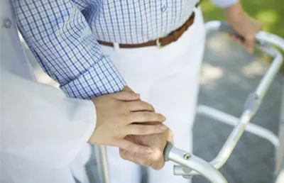 A woman putting her hand over a man's hand. He is holding on to a walker.
