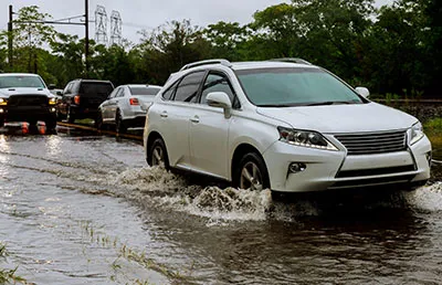A white van driving through a flooded street after a storm.
