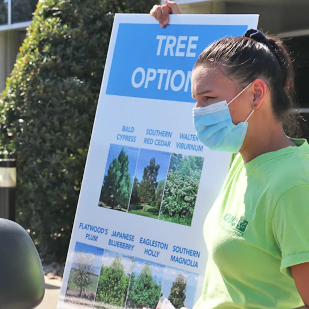 OUC volunteer promoting tree giveaways