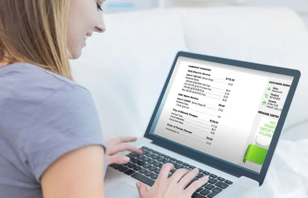 Woman looks at her computer while reviewing her OUC bill.
