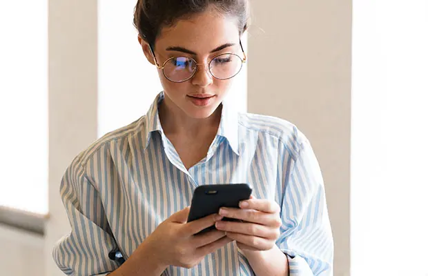 Woman looking at her cell phone, getting ready to call OUC.
