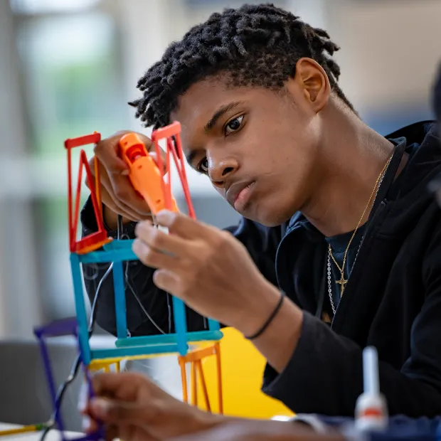Student at the Youth Energy Academy glues popsicle sticks together