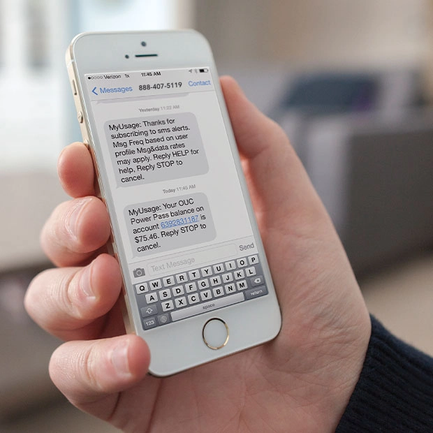 Hands holding a credit card and a cell phone open to myOUC's account summary